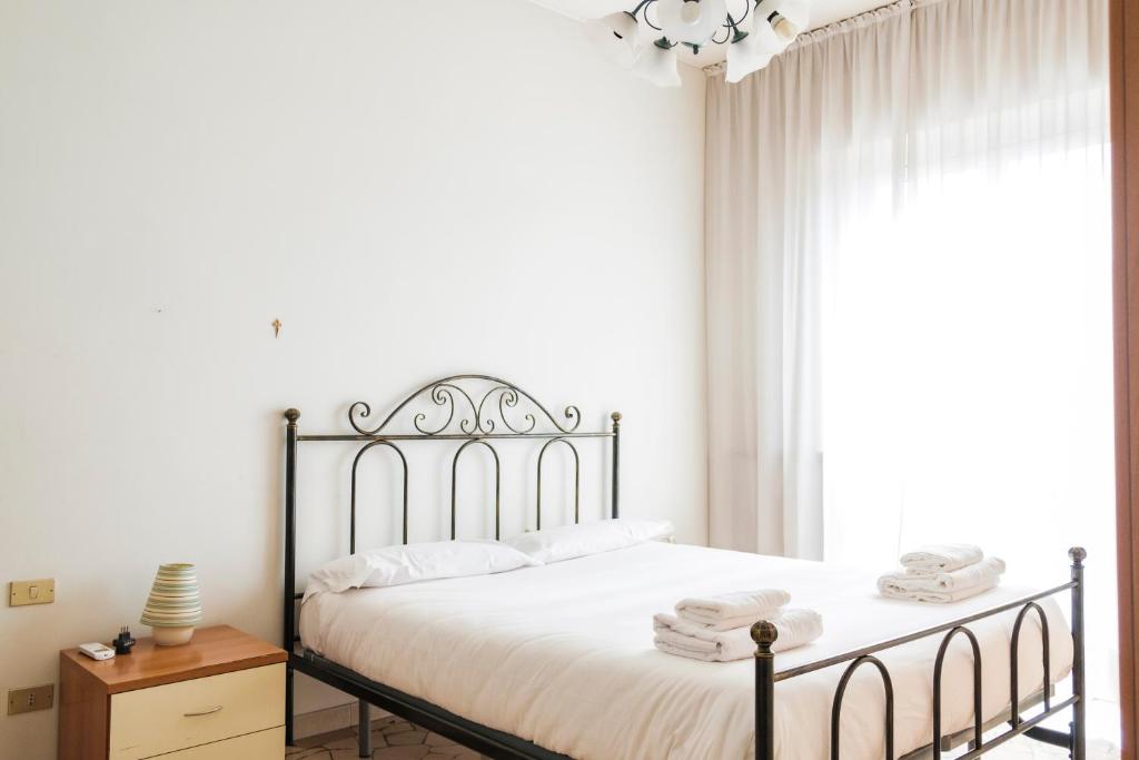 um quarto com uma cama com lençóis brancos e uma janela em Accogliente APT a 750m da Stazione FS e metro em Sesto San Giovanni