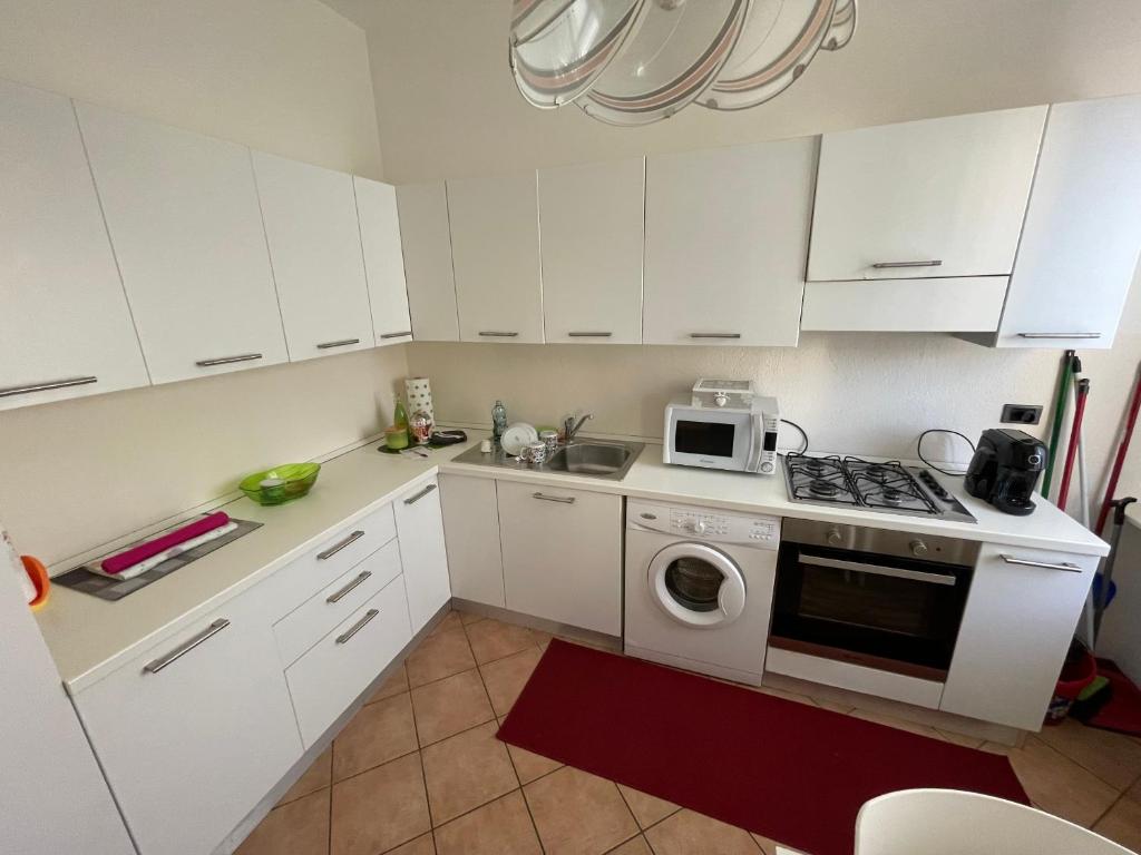a kitchen with white cabinets and a washer and dryer at La Casa dei Sogni in Intra