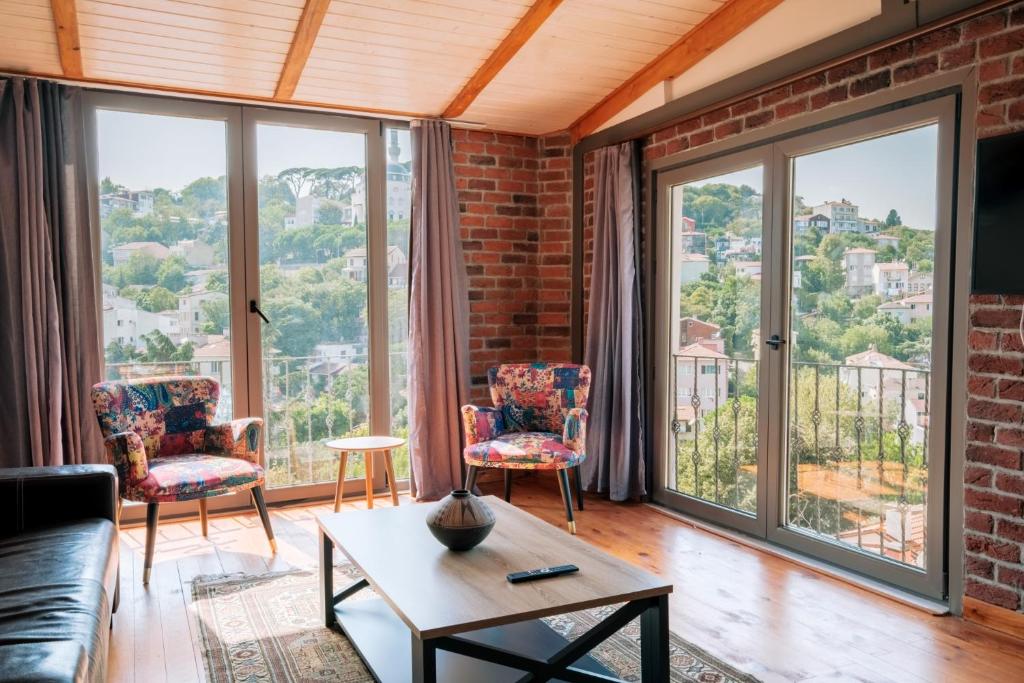 een woonkamer met een bank en stoelen en grote ramen bij Stunning Sea View Loft 5 min to Park in Kuzguncuk in Istanbul