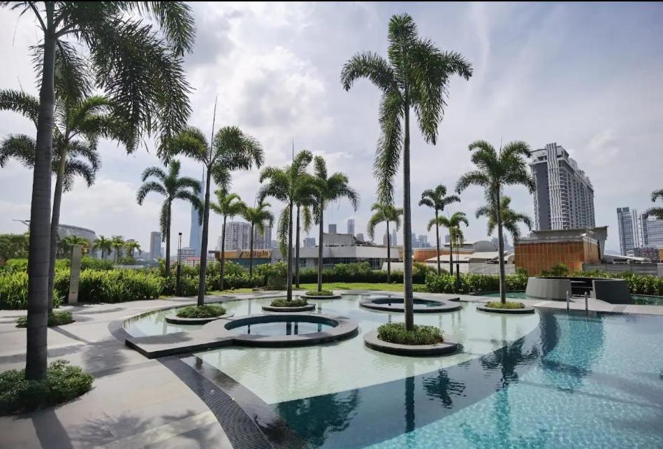 a large swimming pool with palm trees in a city at TRION KL by JRLodge Homestay in Kuala Lumpur
