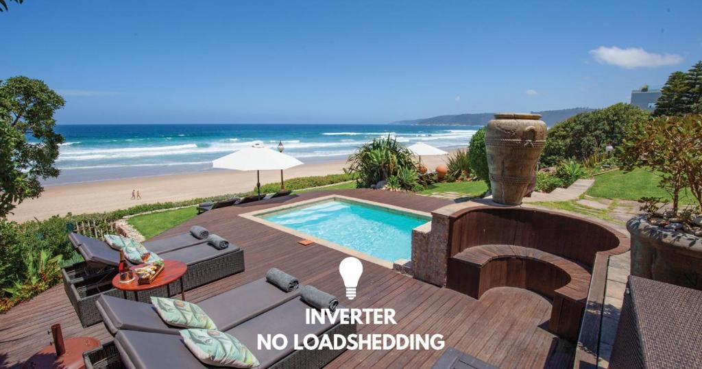 a house with a swimming pool next to a beach at Xanadu Guest Villa in Wilderness