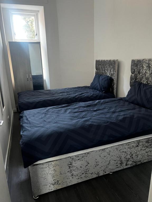 a bedroom with two beds with blue sheets and a mirror at AP Apartment in Glasgow