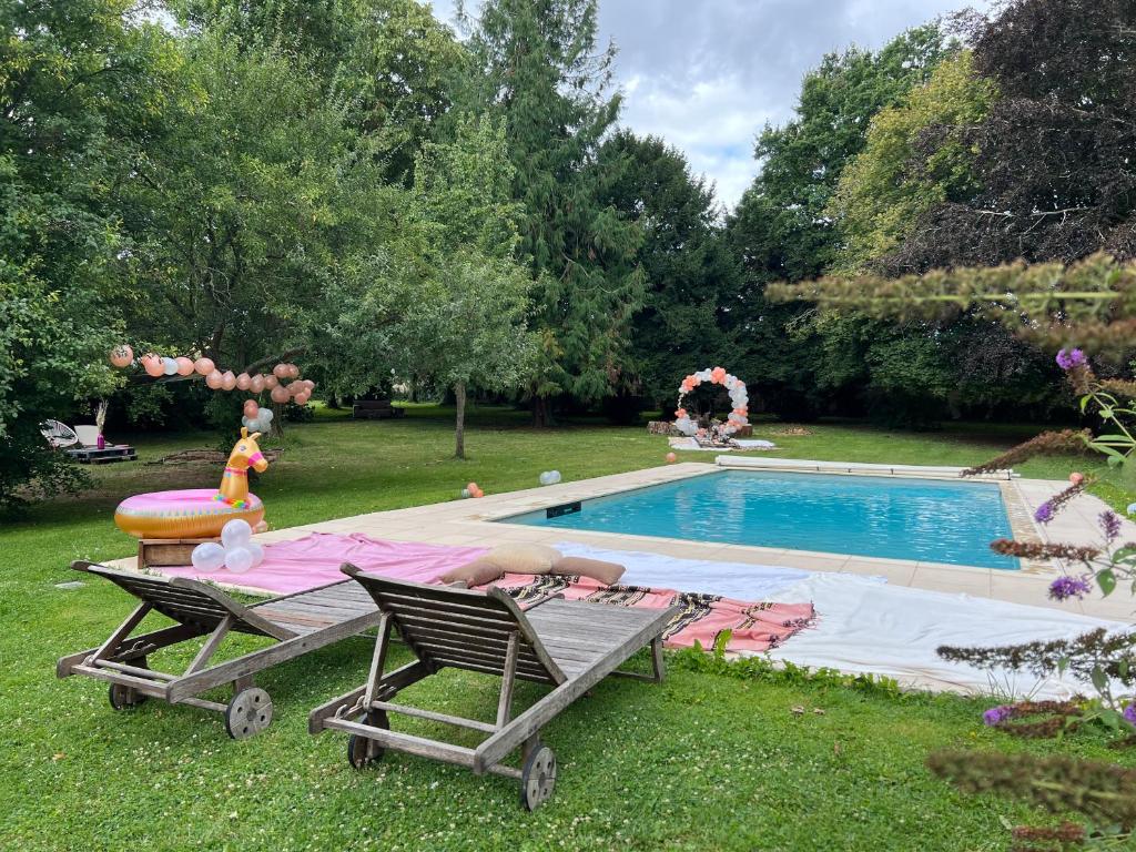 een zwembad met twee stoelen en een tafel ernaast bij Le château de cartes des Massés in Villeneuve-la-Guyard