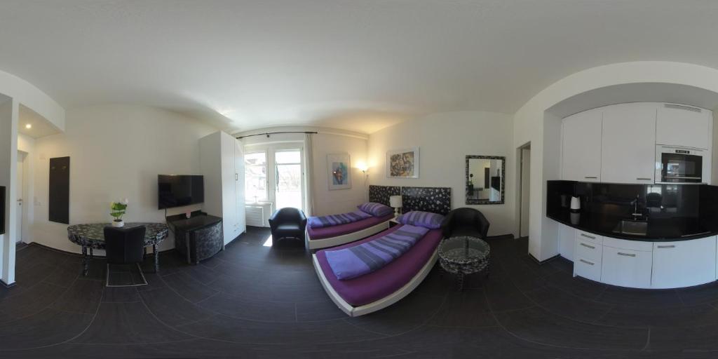 uma sala de estar com um sofá roxo e uma televisão em Seefeld Residenz em Zurique