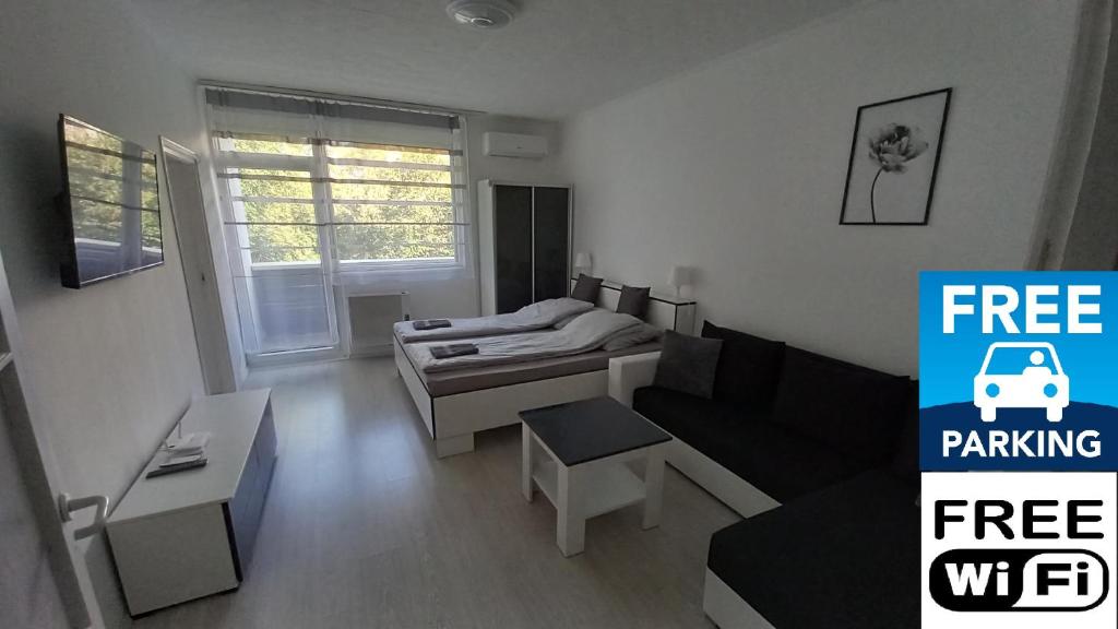 ein kleines Wohnzimmer mit einem Sofa und einem Bett in der Unterkunft Grey Harmony Apartman in Debrecen
