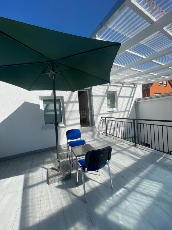 a patio with two chairs and a table with an umbrella at Ferien Wohnung in Rüsselsheim