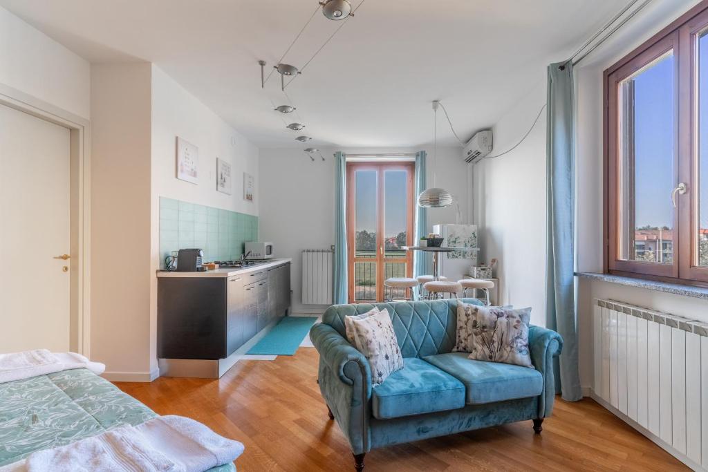 a living room with a blue couch and a kitchen at CasaTella - Monolocale - letto matrimoniale - angolo cottura - bagno e balcone in Vidigulfo