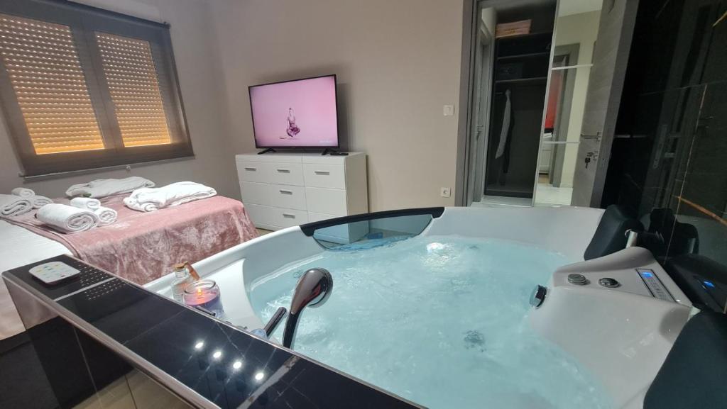 a bathroom with a tub with a television and a bed at Mias luxury spa apartment in Rijeka