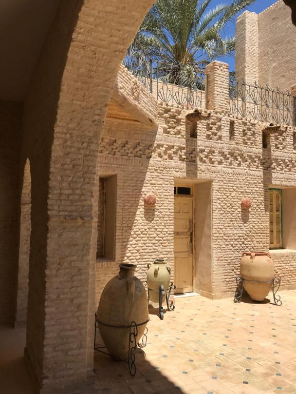 een gebouw met twee grote vazen op een binnenplaats bij Dar Aron Tozeur in Tozeur