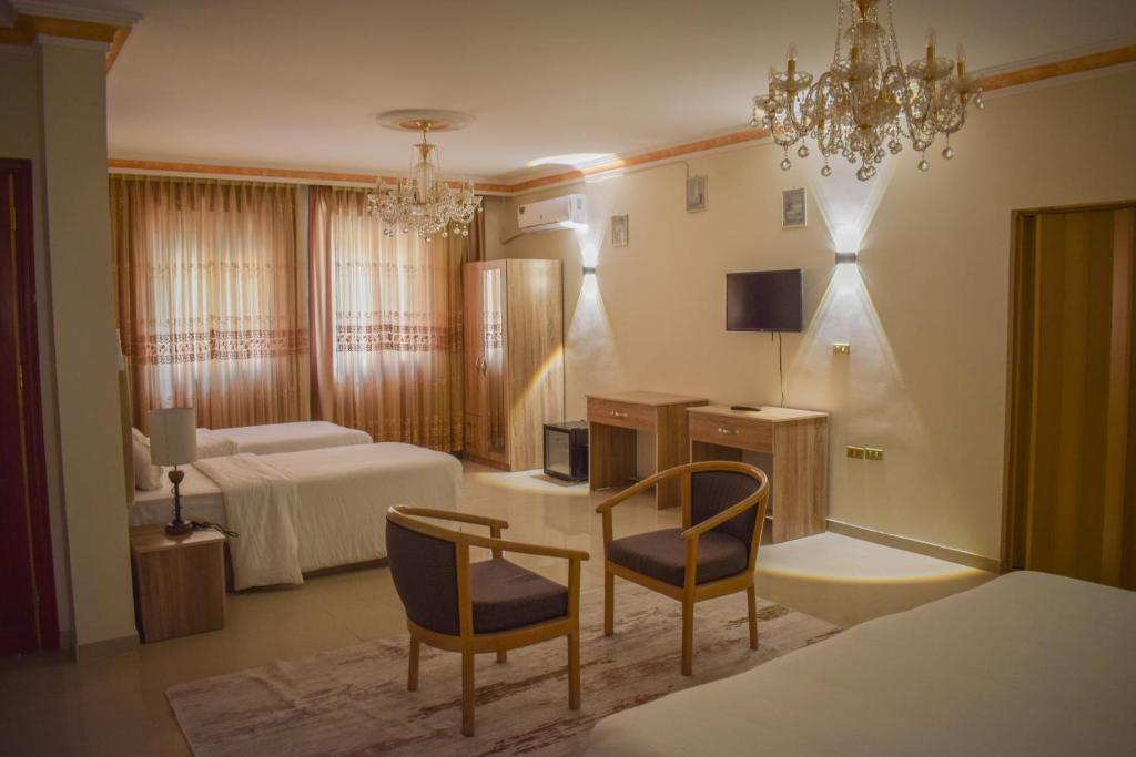 a hotel room with a bedroom with a bed and two chairs at Twilight Hotel Petra in Wadi Musa
