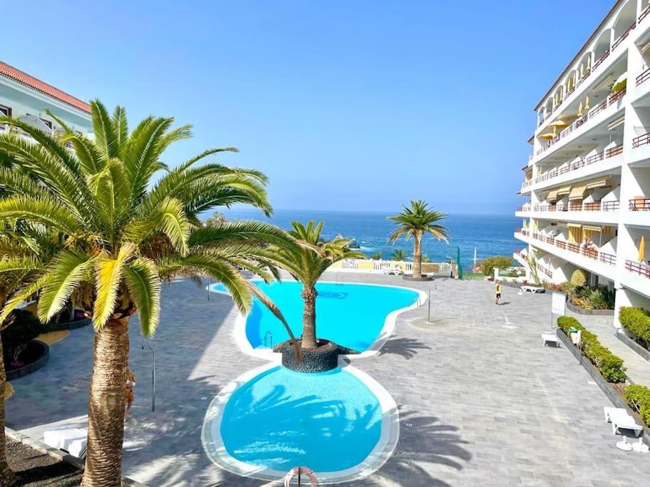 a view of a resort with palm trees and a swimming pool at TAGARA - 2 pools, ocean view, Puerto de Santiago in Puerto de Santiago