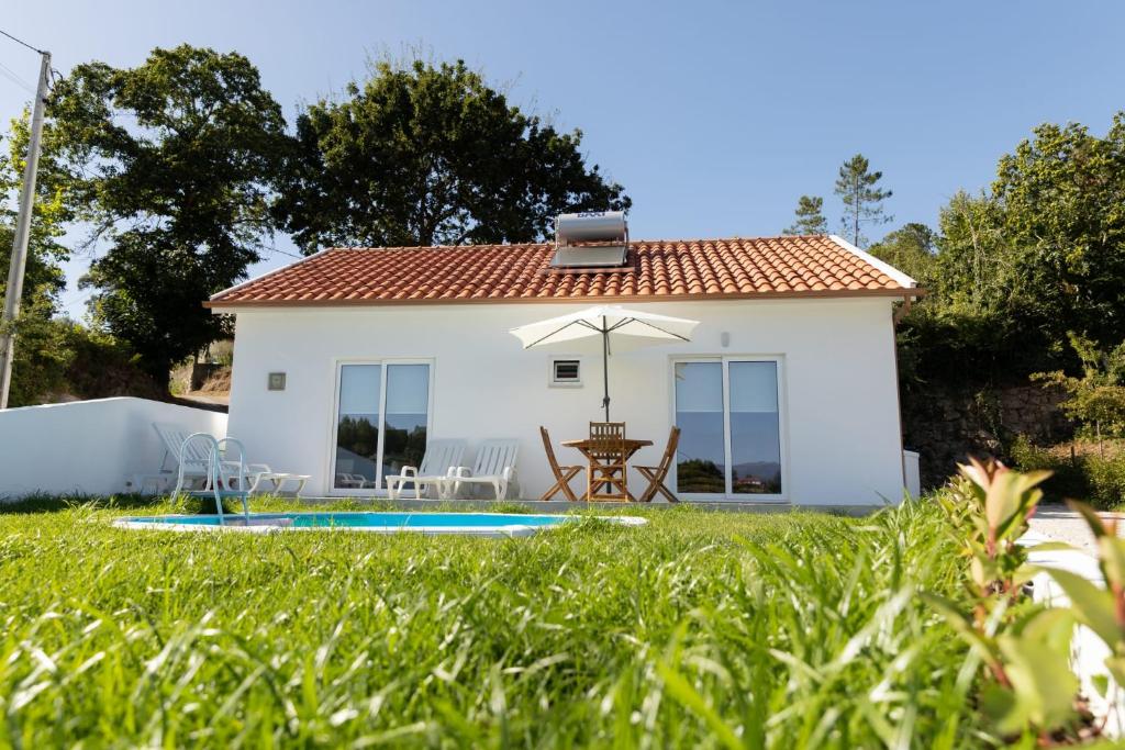 een klein wit huis met een zwembad in de tuin bij Refugio das Vinhas in Celorico de Basto