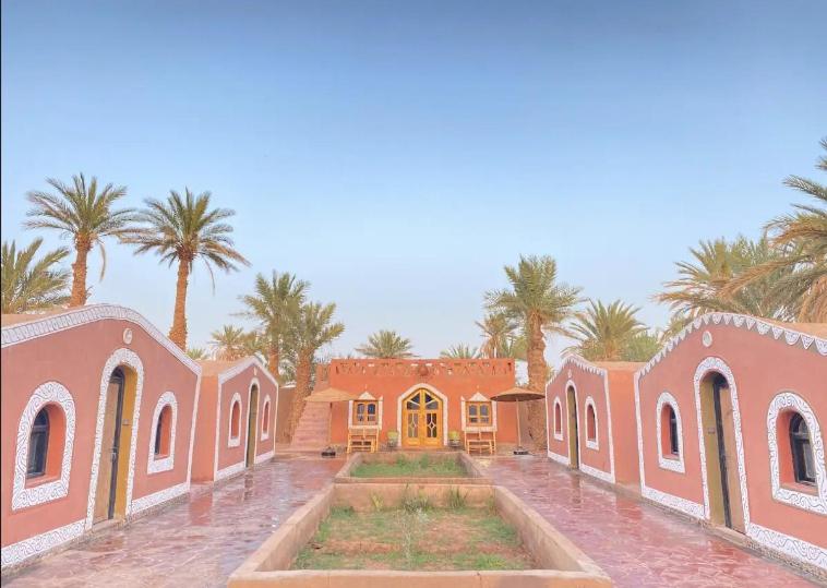 una gran casa rosa con palmeras en el fondo en Billion Stars Desert Camp, en Mhamid
