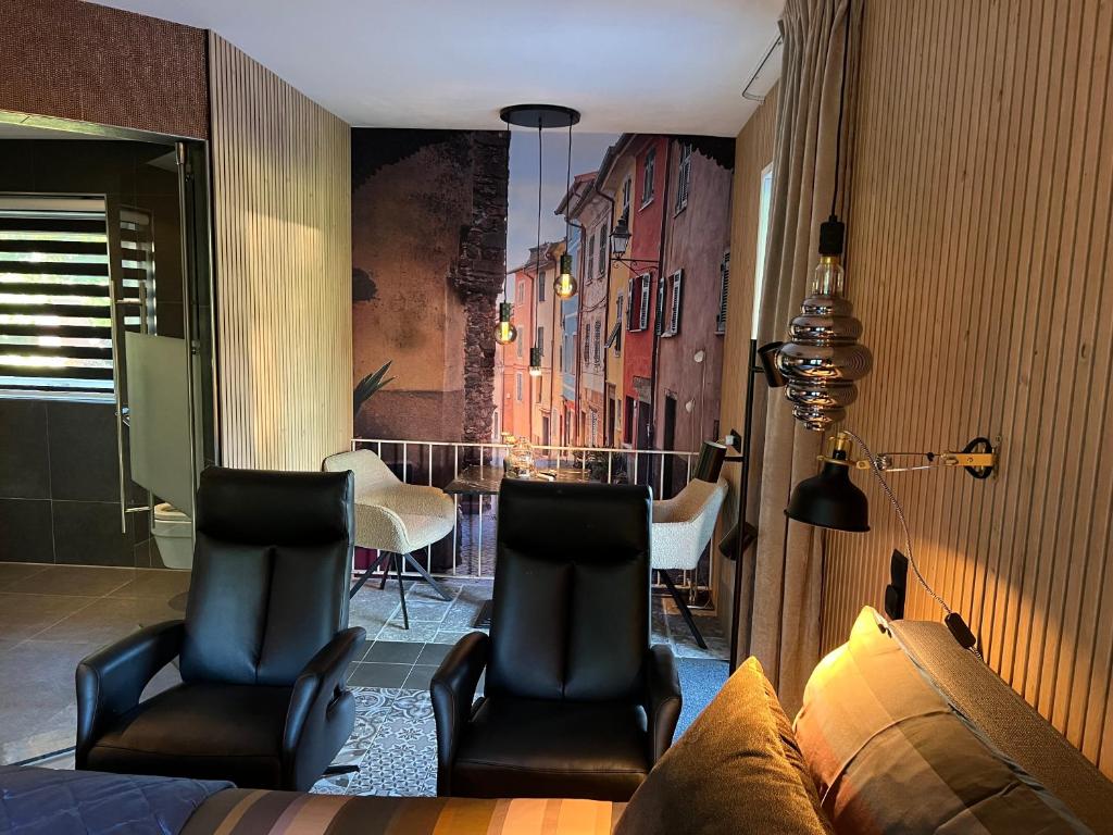 uma sala de estar com duas cadeiras e um sofá em Luxe Mediterraanse Suite em Rijssen