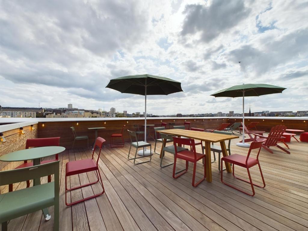 un patio avec des tables, des chaises et des parasols sur le toit dans l'établissement Hife Gentilly Paris Sud Porte d'Italie, à Gentilly