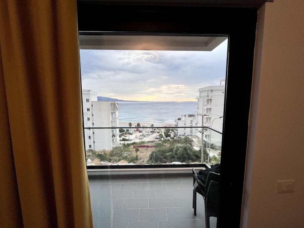 a window with a view of the ocean from a building at Alma's appartament in Sarandë