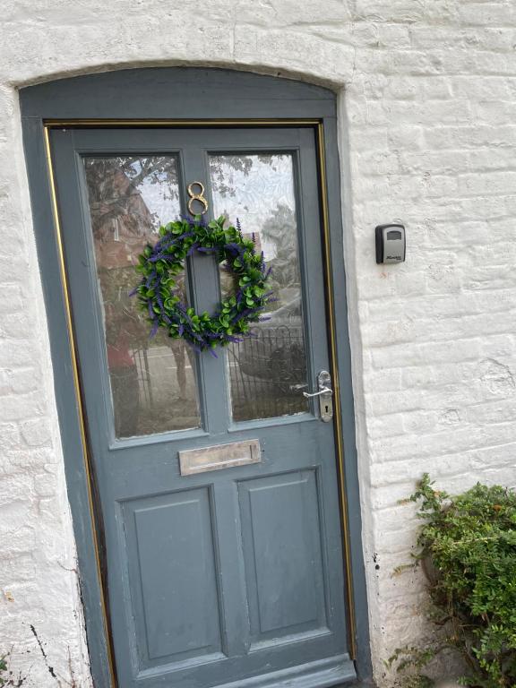 Una porta blu con una corona di fiori di Charming cottage a Lyng