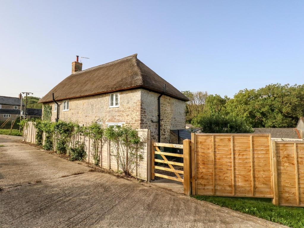 an old brick house with a wooden fence at Dairy Cottage in Weymouth