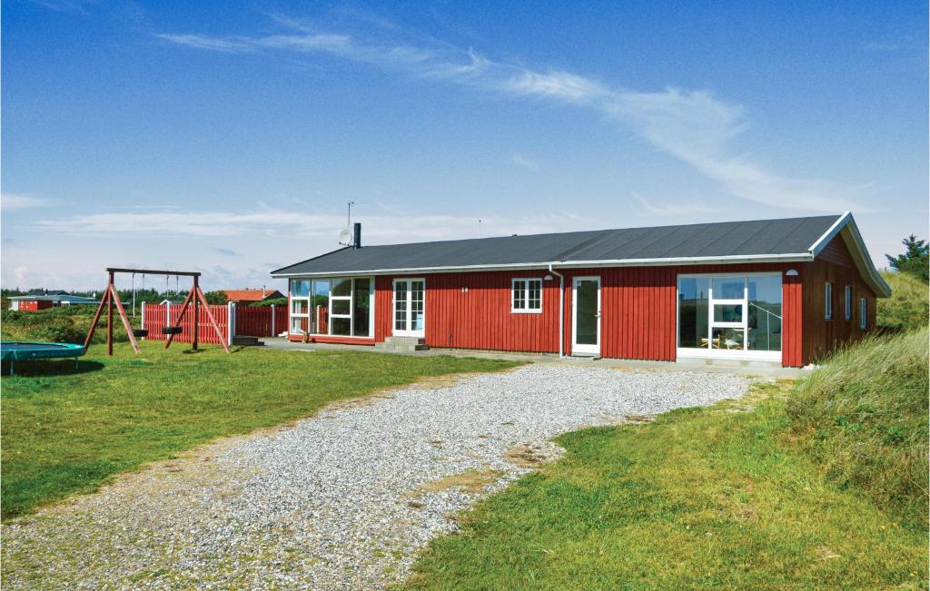 a red house with a playground and a swing at Awesome Home In Ringkbing With 3 Bedrooms, Sauna And Wifi in Søndervig