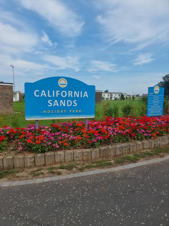 a sign for california sands holiday park with flowers at Sands Holiday Chalet Dog friendly, free wifi, swimming pool and club passes included in Scratby