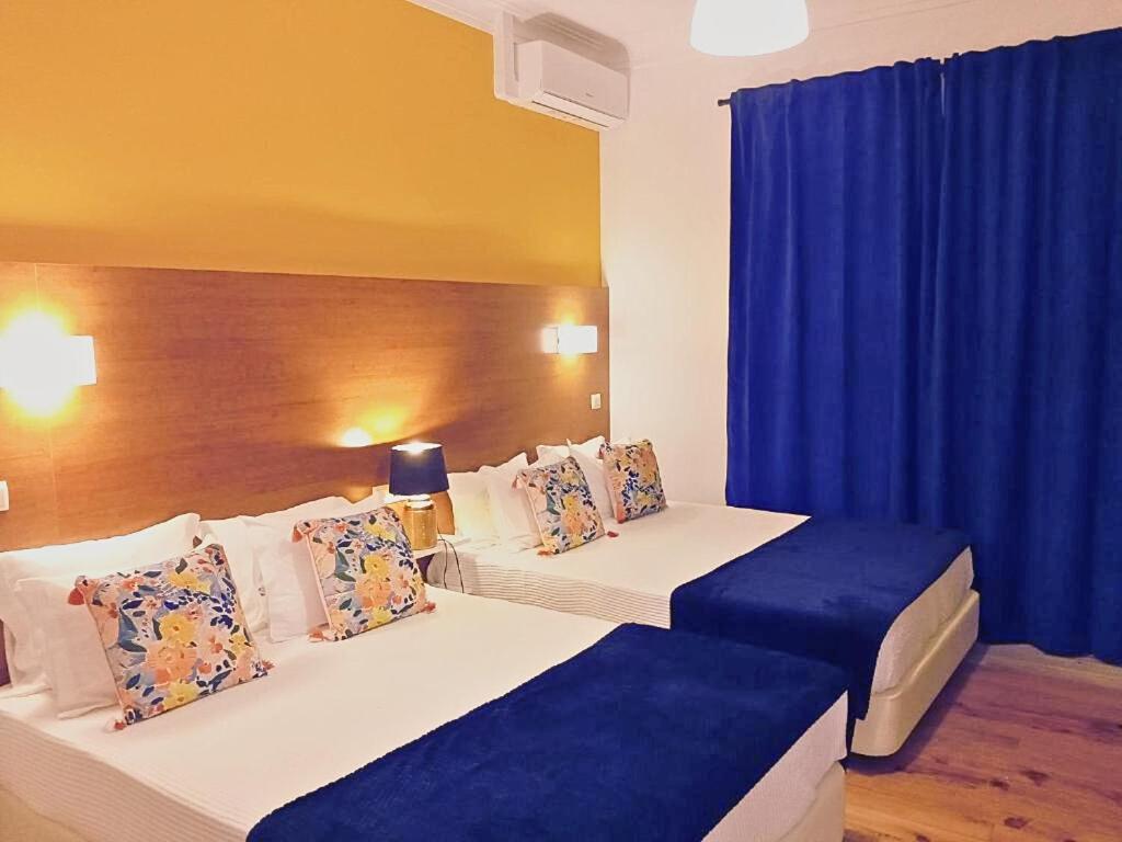 2 łóżka w pokoju hotelowym z niebieskimi zasłonami w obiekcie Corredoura Garden w mieście Caldelas