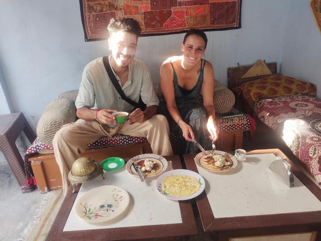 a man and a woman sitting on a couch with food at Little prince guest house & homestay in Bikaner