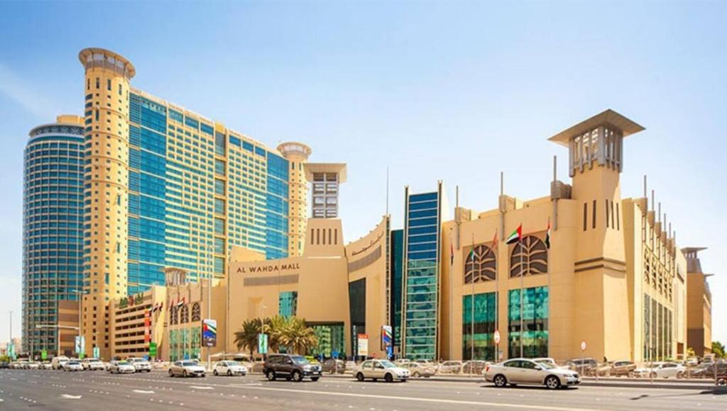 un gran edificio con coches estacionados frente a él en International Abu Dhabi Hostel, en Abu Dabi