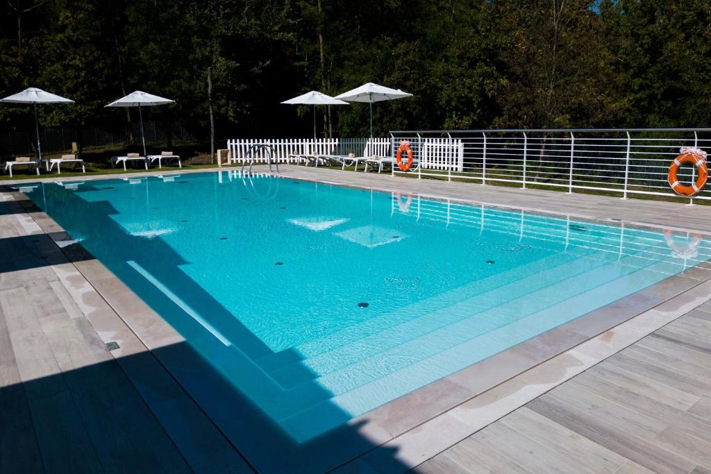 una gran piscina azul con sillas y sombrillas en Four Points by Sheraton Siena, en Siena