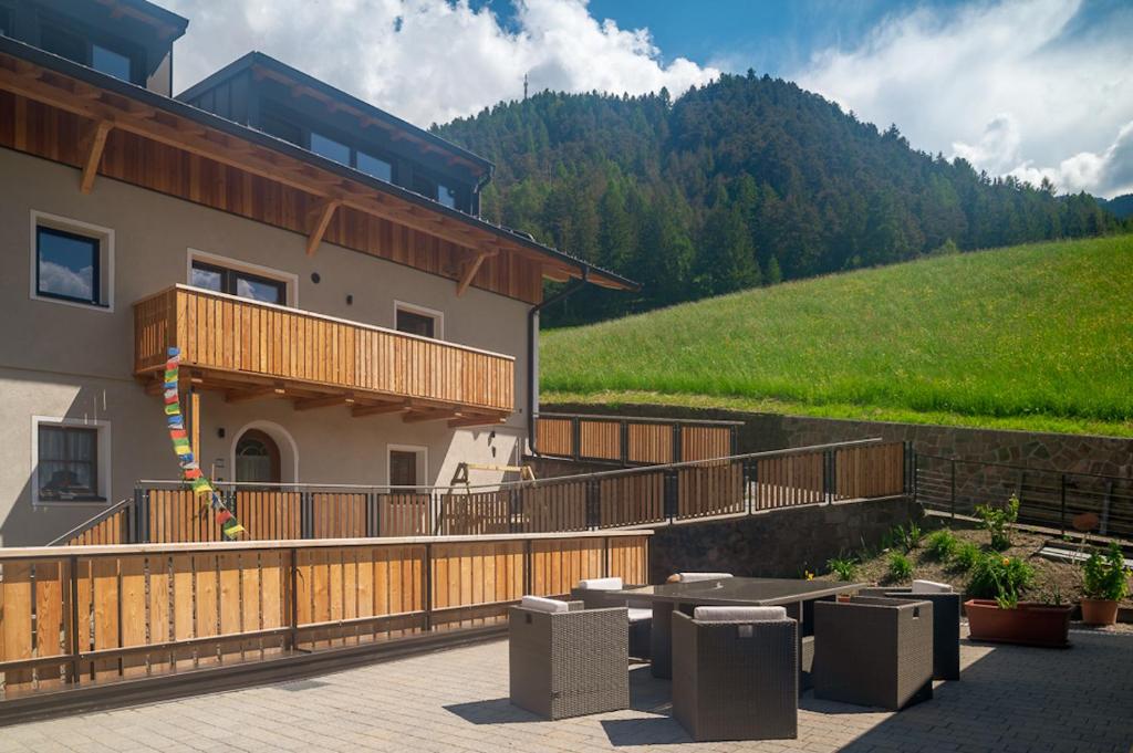 a building with a deck and a hill in the background at Planerhof Apartment Lilie in Funes