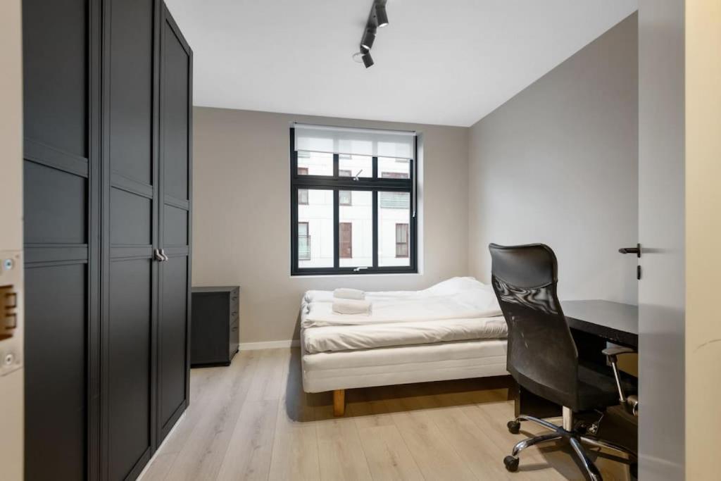 um quarto com uma cama, uma secretária e uma cadeira em Dinbnb Apartments I New 2021 I Affordable Option em Bergen