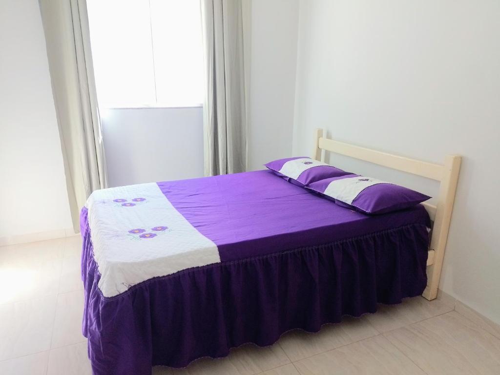 Schlafzimmer mit einem Bett mit lila und weißen Laken in der Unterkunft Casa de temporada - Raio de luz! in Carolina