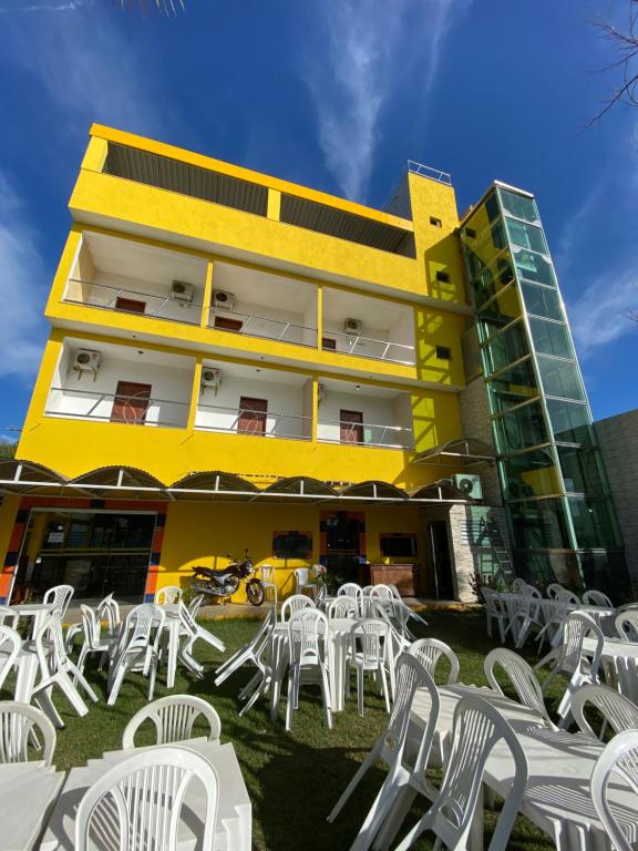 Chesmar Plaza Hotel في فيرا كروز دو إيتاباريكا: مجموعة من الطاولات والكراسي البيضاء أمام المبنى