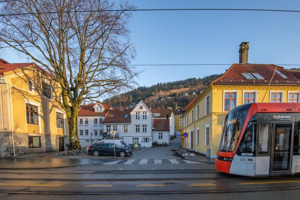 a red and white bus on a street with buildings at Dinbnb Apartments I Cozy 1-Bedroom Nestled in the Heart of Bergen in Bergen