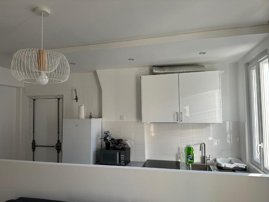 a kitchen with white cabinets and a sink at La Résidence élégante in Saint-Denis