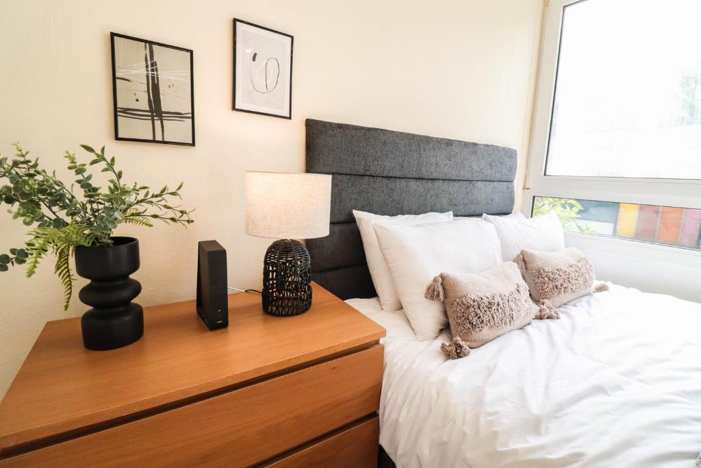 ein Schlafzimmer mit einem Bett mit einer Holzkommode und einer Lampe in der Unterkunft Cosy property right by WARREN STREET station! FREE WIFI! in London