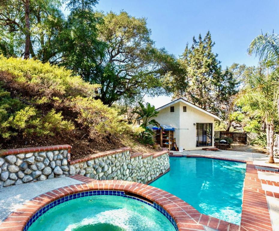 a swimming pool with a brick retaining wall next to a house at NEW Modern apt w/pool & hot tub in nature in Thousand Oaks