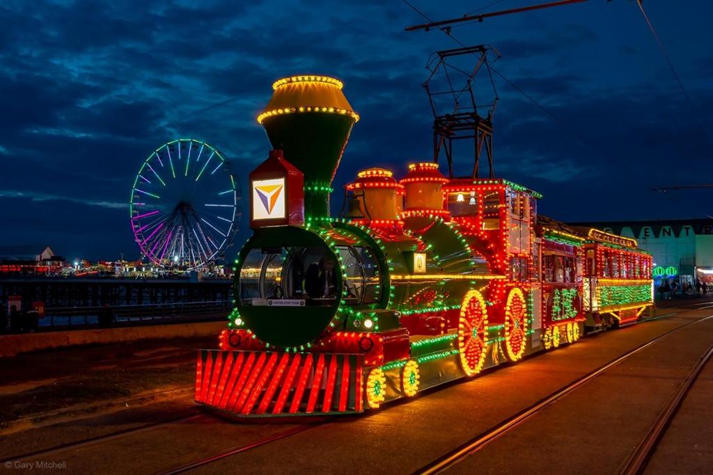 un tren cubierto de luces de Navidad con una noria en Adina Hotel, en Blackpool