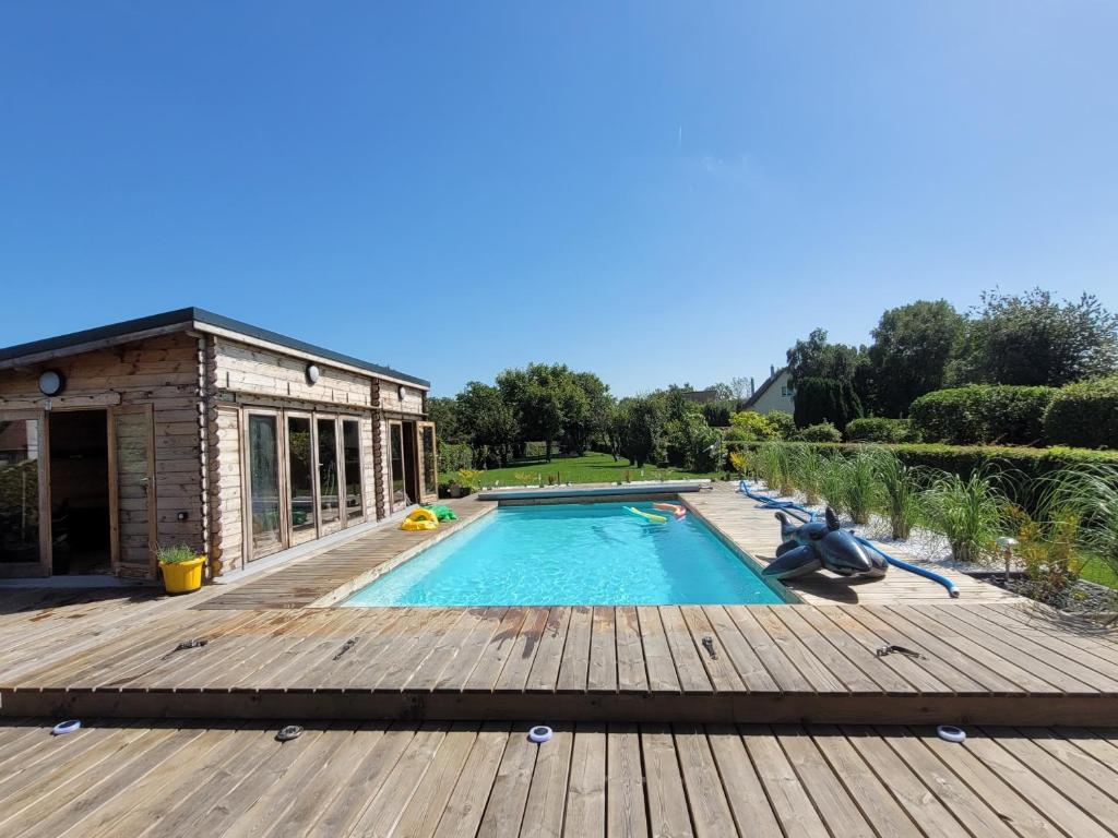 a swimming pool with a wooden deck and a building at Villa Oriel avec piscine privée à NEUFCHATEL-HARDELOT in Neufchâtel-Hardelot