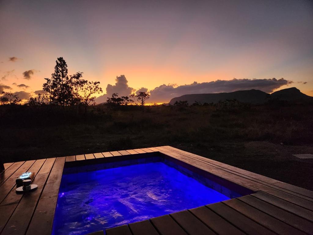 a hot tub on a deck with a sunset in the background at Banglo in Alto Paraíso de Goiás