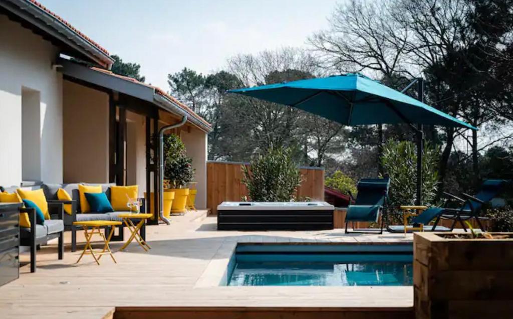 une terrasse avec des chaises et un parasol ainsi qu'une piscine dans l'établissement La villa du lac Biscarosse, à Biscarrosse