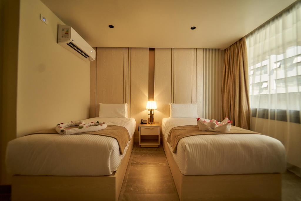 2 camas en una habitación con ventana en Gold's Pyramids Hotel, en El Cairo