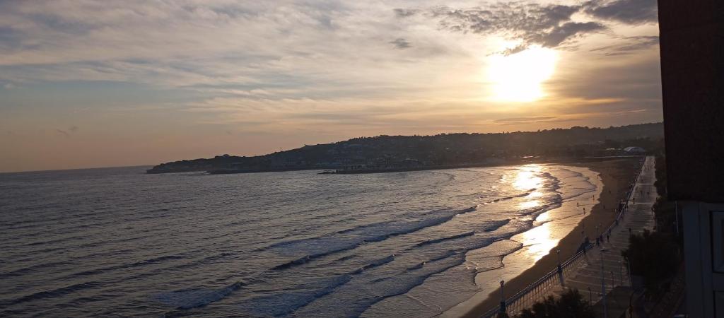 a beach with the sun setting over the water at Encanto del Cantábrico in Gijón