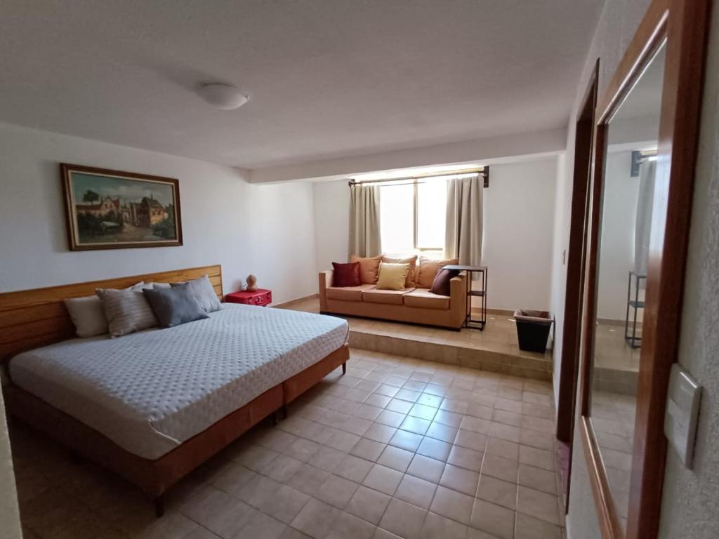 sypialnia z łóżkiem i kanapą w pokoju w obiekcie Casa Arena w mieście Casa Blanca La Corregidora