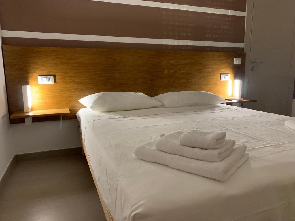 a white bed with a pile of towels on it at La Casa di Toni in Pescara