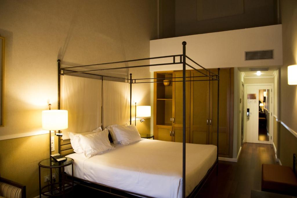 a bedroom with a large white bed with a metal frame at Hotel Nuevo Portil Golf in El Rompido