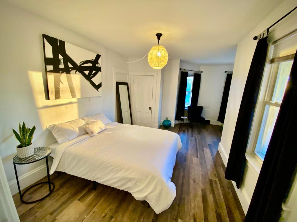 a bedroom with a white bed and a pendant light at Lakes Region Gem - Chic Victorian Apt - Laconia in Laconia