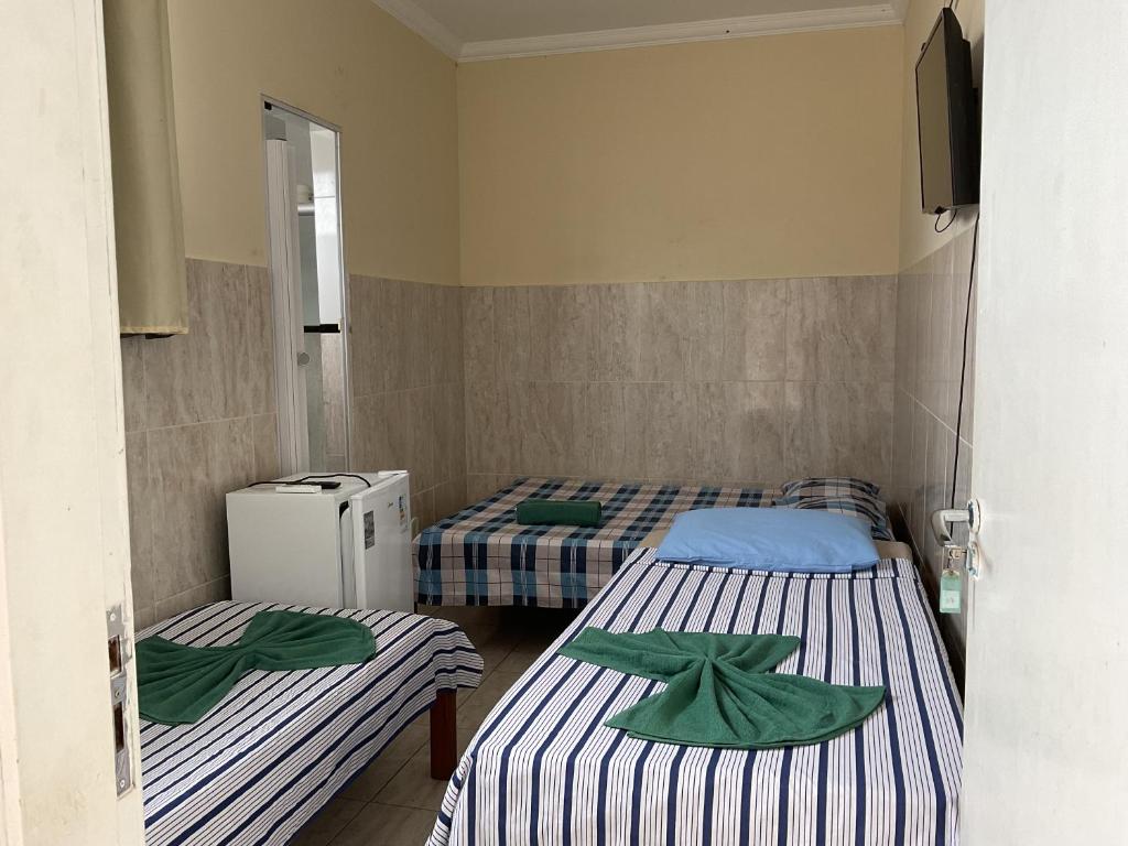 a room with two beds and a refrigerator in it at Pousada Pitanga in Maceió