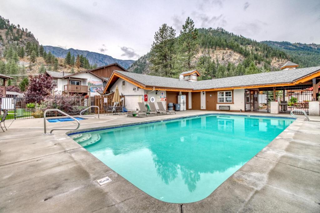 a swimming pool in front of a house with a mountain at Icicle Village Resort 401 Aspen Abode in Leavenworth