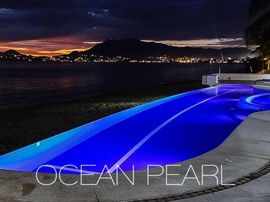 uma piscina azul com vista para o oceano à noite em The Ocean Pearl Beachfront Infinity Pool Gym BBQ em Manzanillo