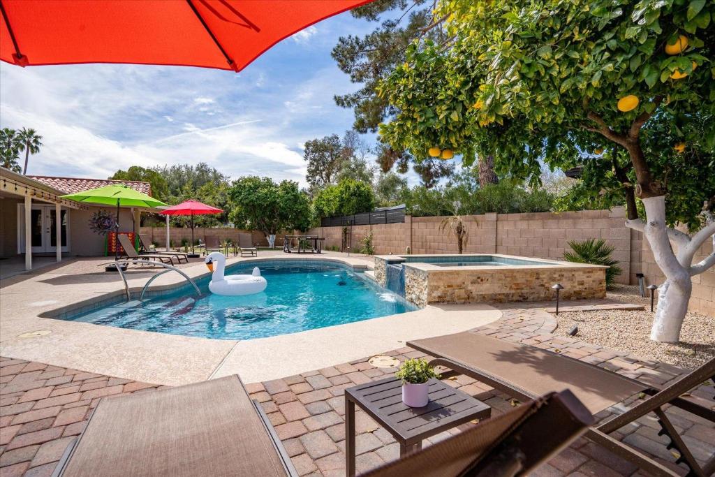 a swimming pool with a red umbrella and a swimming pool at The Rusty Cactus in Phoenix